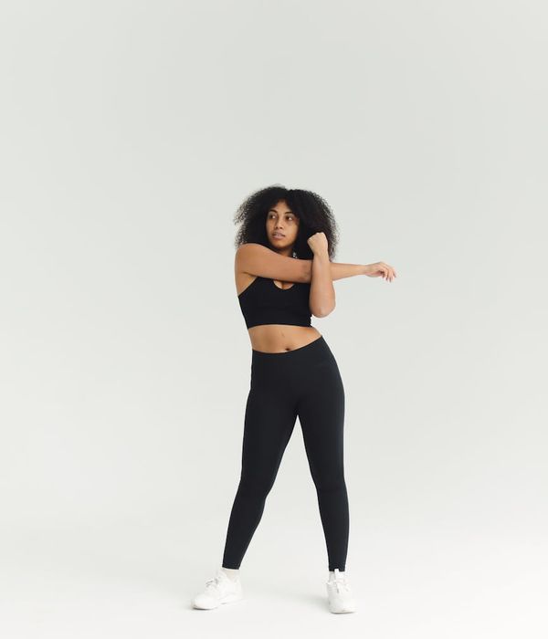 Woman in a dynamic cardio pose in a minimalist dark studio.